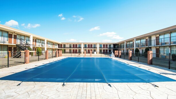A courtyard with a swimming pool, brick pillars, and a multi-story building with balconies. - OYO Hotel Oklahoma City South I-35 and SE 29th (Oklahoma City)