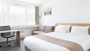 Habitació d'hotel amb llit, escriptori, cadira i sofà.