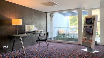 Habitación de hotel con escritorio, computadora, silla y una ventana grande con vistas al exterior.