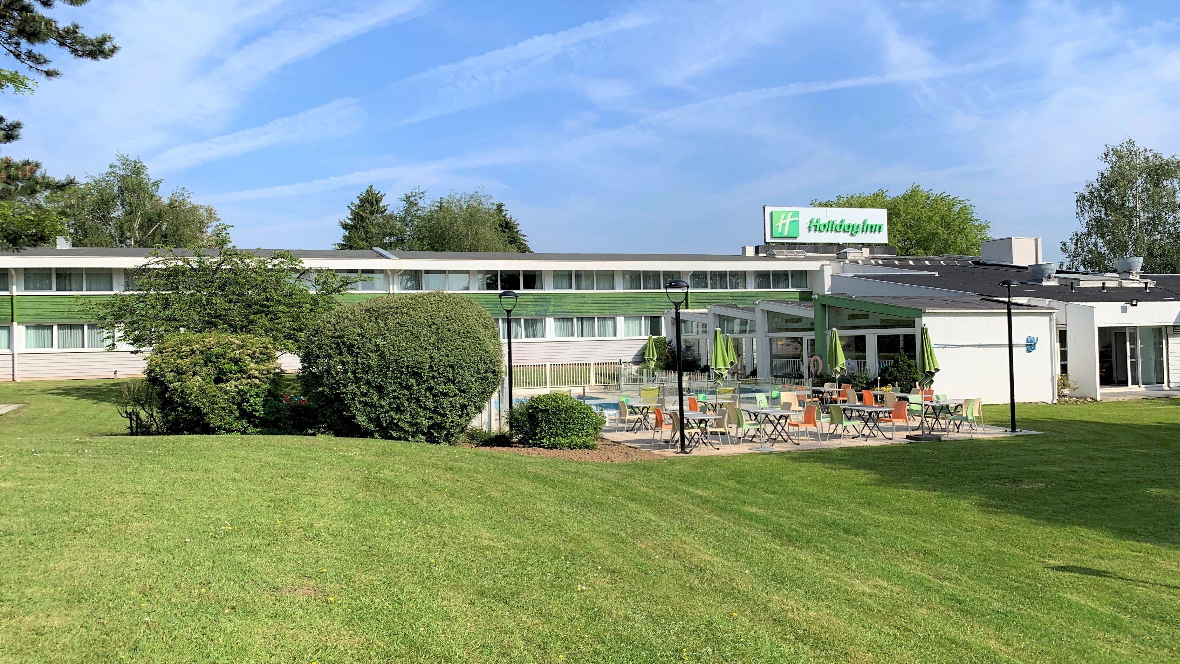 Un hôtel Holiday Inn doté d’une piscine, d’un espace extérieur aménagé avec des sièges et d’une pelouse bien entretenue.