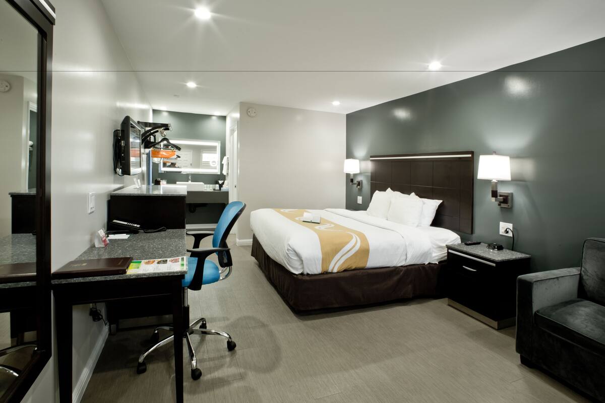 Una habitación de hotel moderna con cama, escritorio, silla y una mesita.