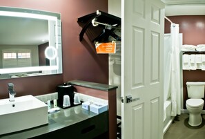 A bathroom with a mirror, sink, and toiletries.