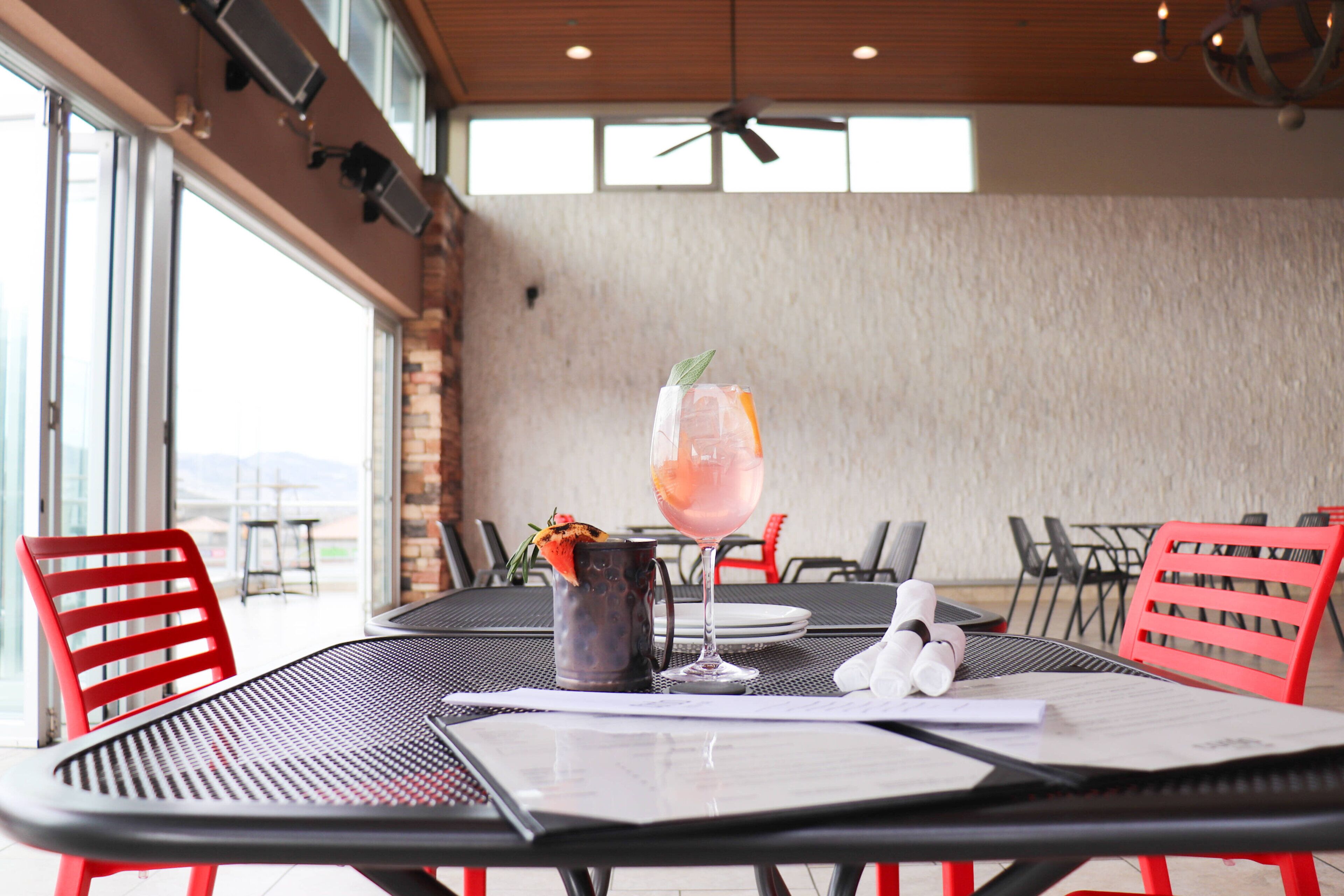 A dining area with a table set for two, featuring a drink, a pitcher, and a menu.
