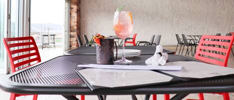 A dining area with a table set for two, featuring a drink, a pitcher, and a menu.