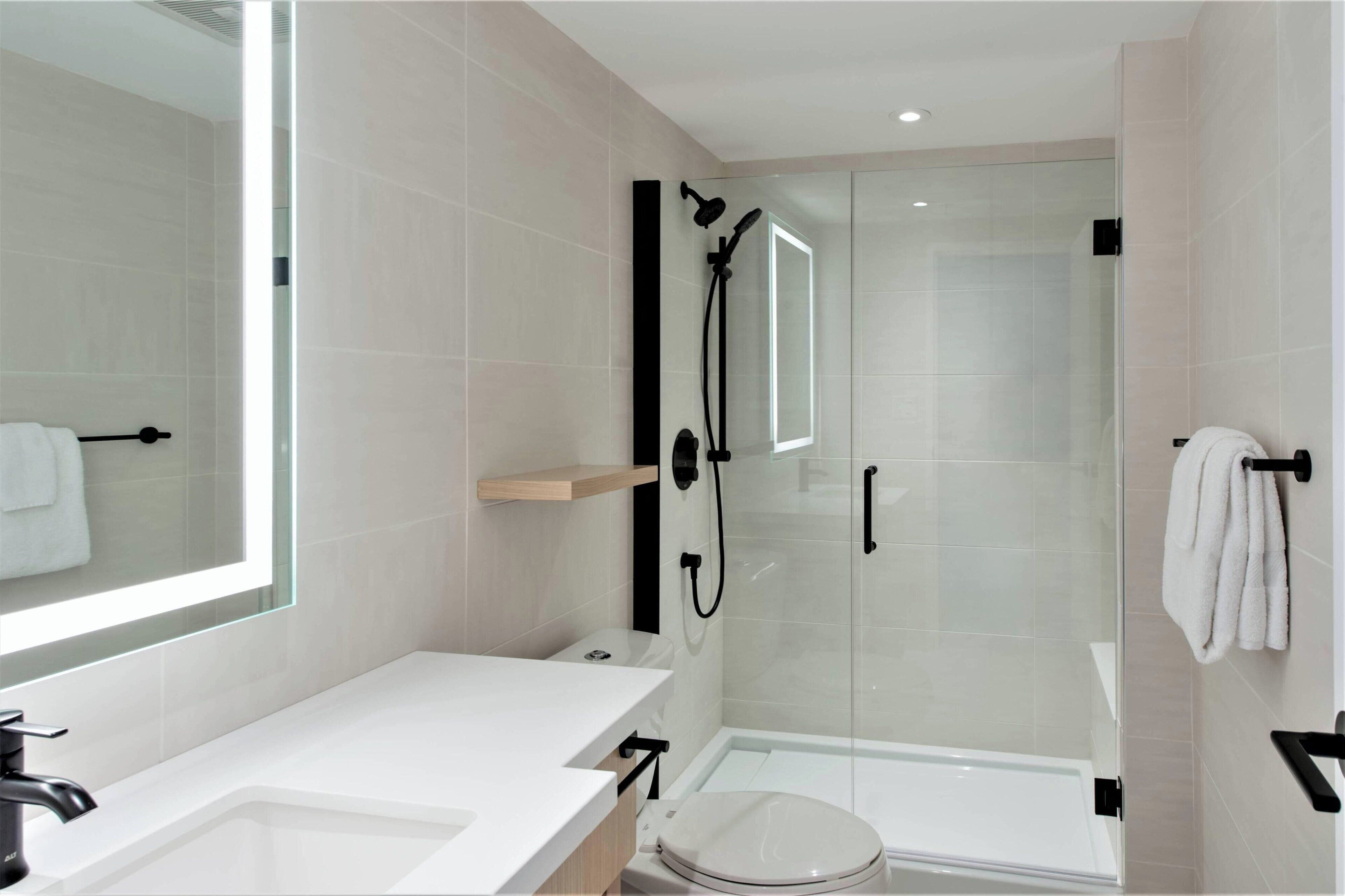 A modern bathroom with a glass-enclosed shower, a white sink, and a toilet.