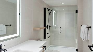 A modern bathroom with a glass-enclosed shower, a white sink, and a toilet.
