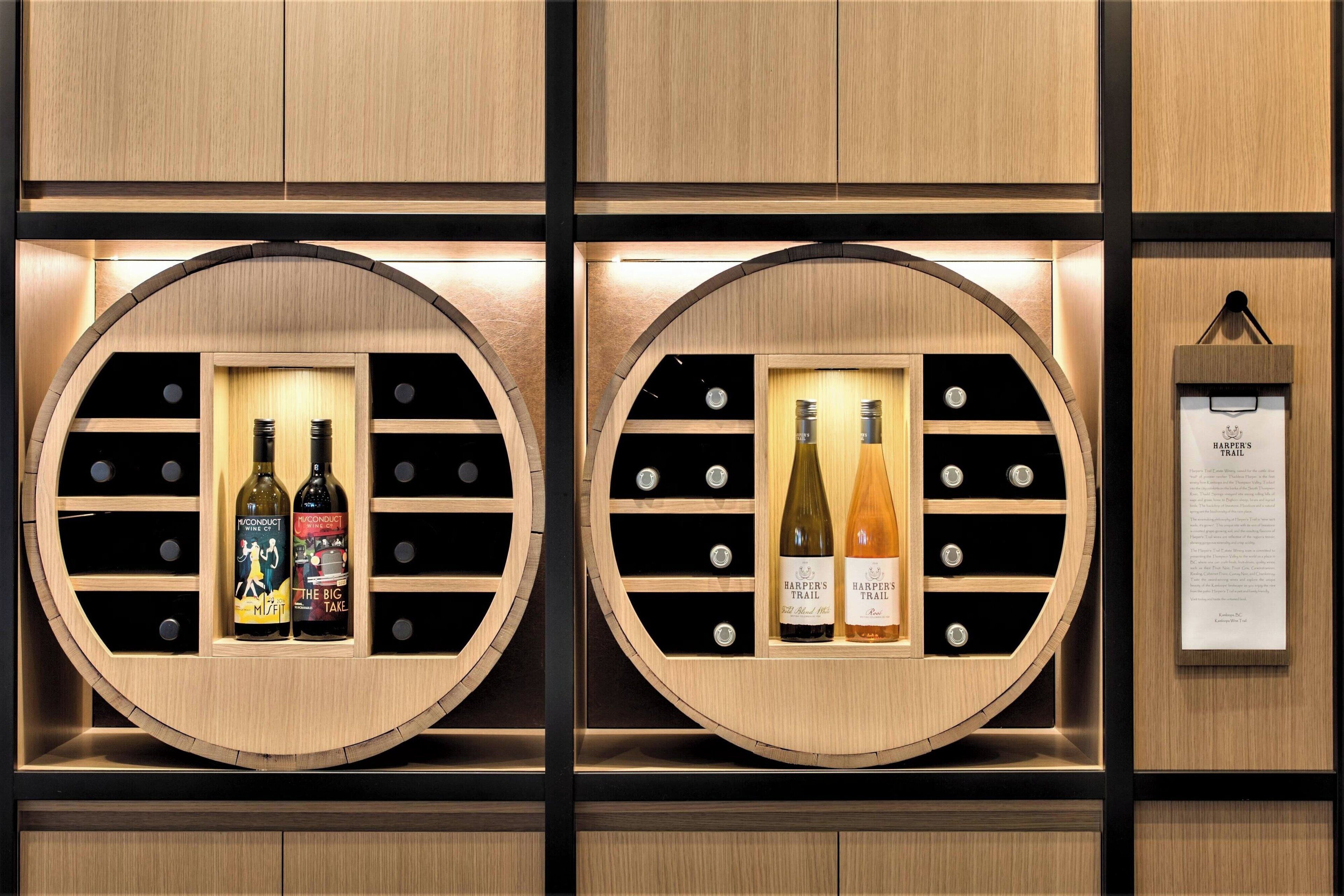 Deux présentoirs à vin circulaires en bois, contenant des bouteilles étiquetées « Harper's Trail » et « The Big Take ».