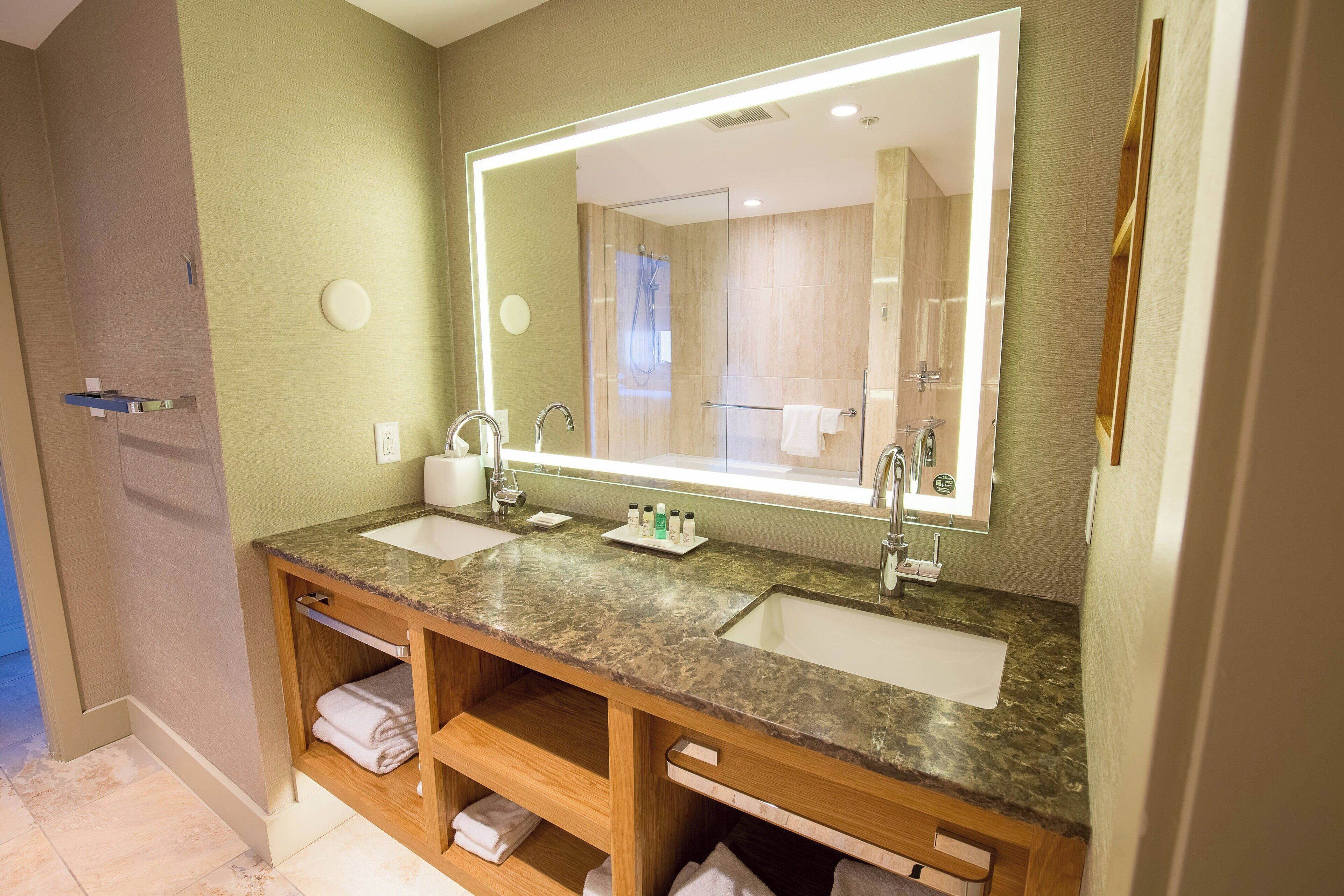 Une salle de bain moderne avec deux vasques, un grand miroir et des meubles-lavabos en bois.