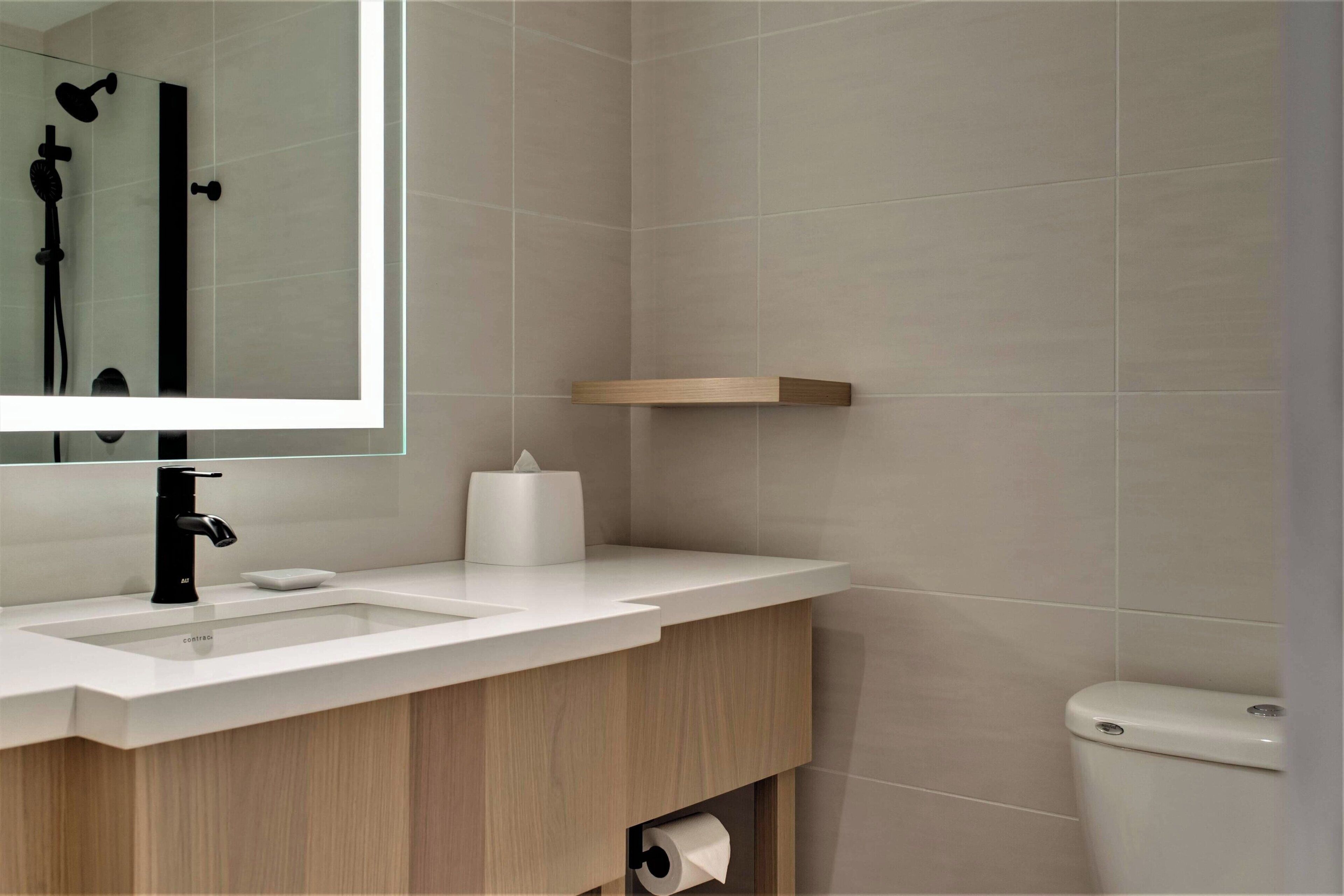 A modern bathroom with a white sink, mirror, and toilet.