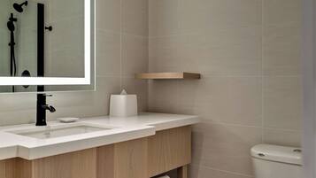 A modern bathroom with a white sink, mirror, and toilet.