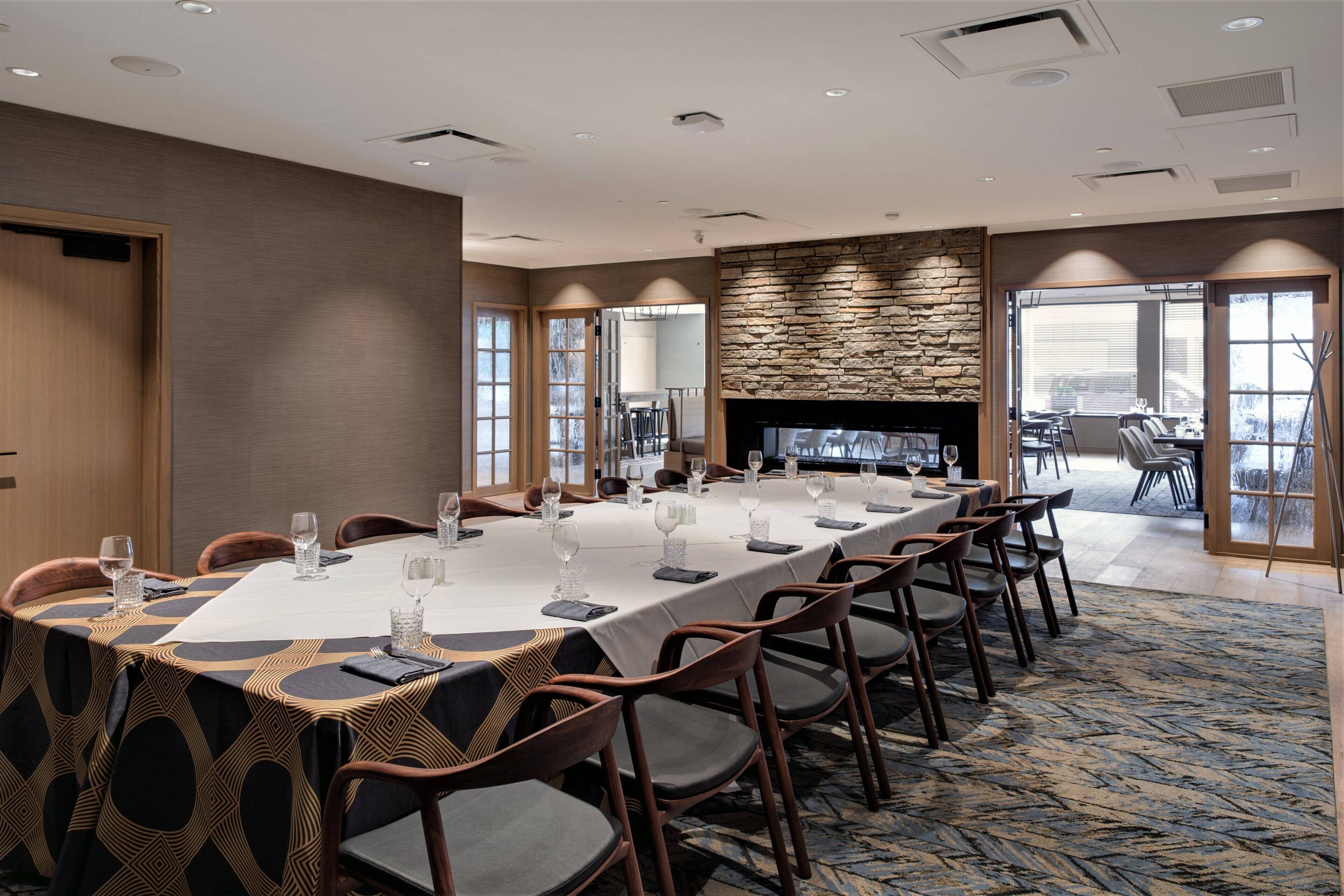 A conference room with a long table, chairs, and a stone fireplace.