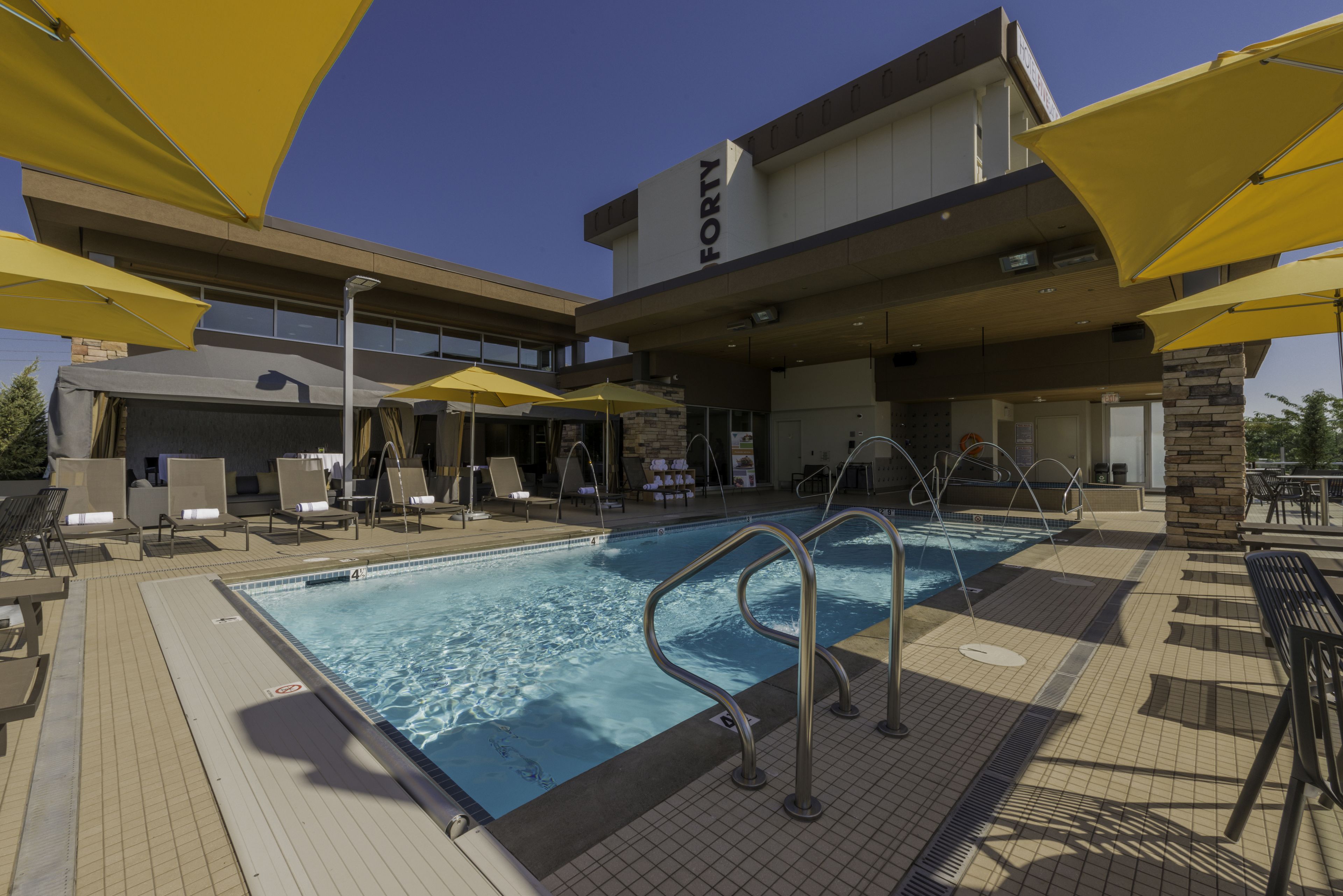 A pool area with yellow umbrellas, lounge chairs, and a sign that reads "FORTY".
