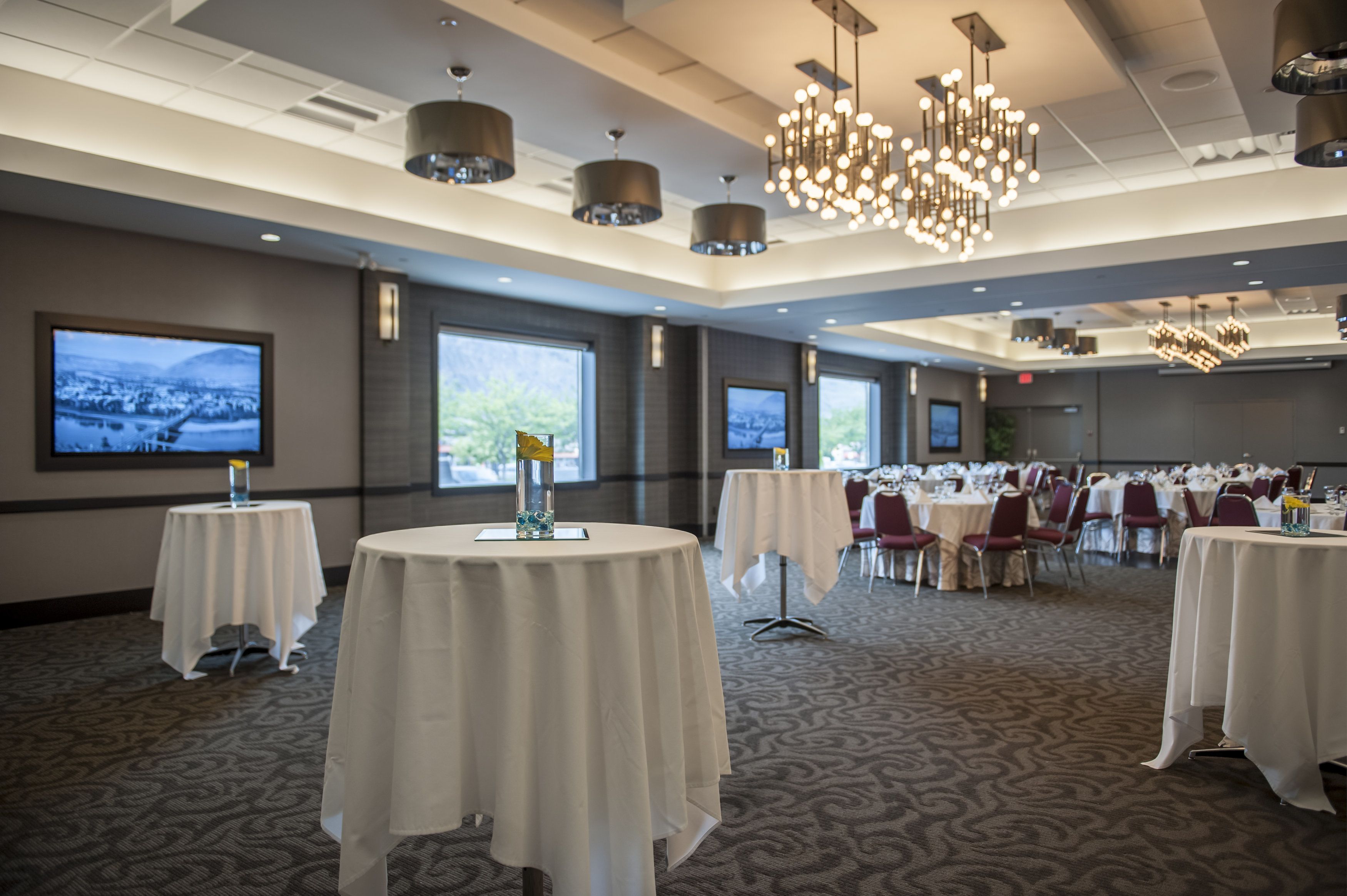 A conference room with round tables, large windows, and a chandelier.