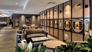 Un moderno vestíbulo de hotel con zonas de estar, un mostrador de recepción y una pared con espejos circulares.