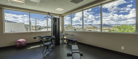 Une salle de sport équipée de matériel d’exercice, dotée de grandes fenêtres et offrant une vue sur l’extérieur.