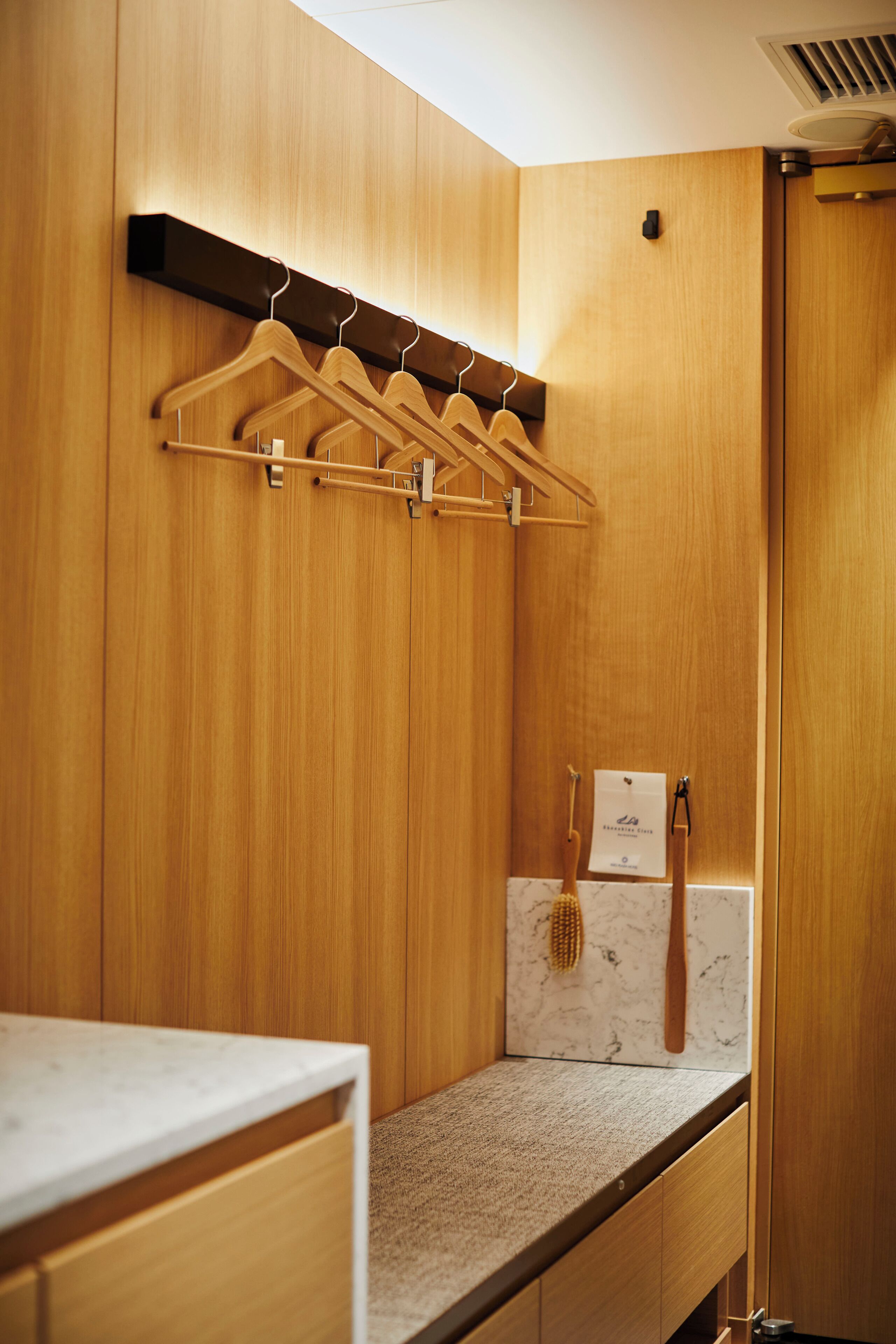 A wooden bathroom with a towel rack, a marble countertop, and a wooden cabinet.