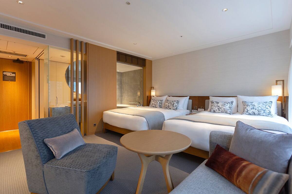 A hotel room with a bed, two bedside tables, a sofa, and a chair.