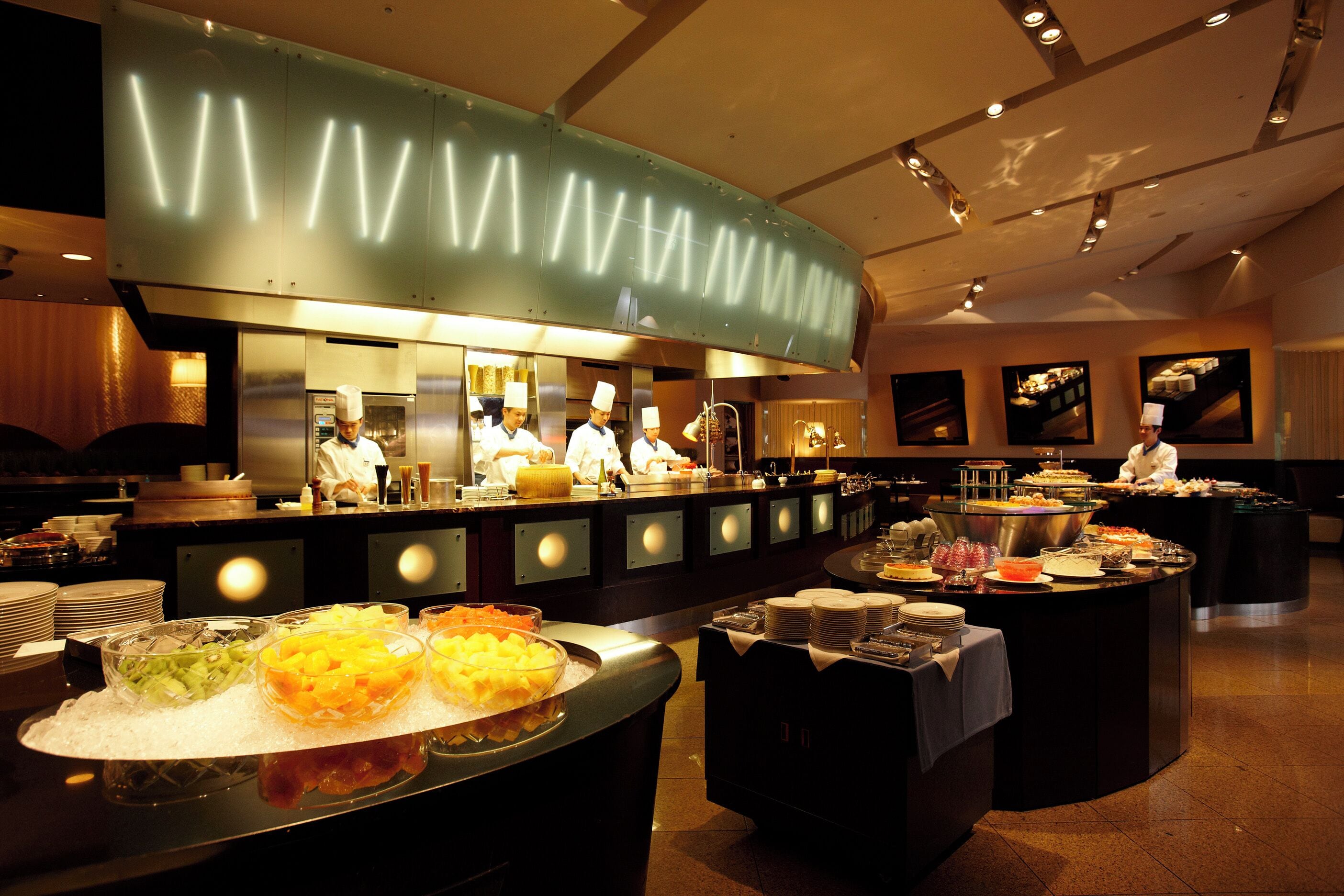 A buffet setup with various food items and a kitchen area in the background.