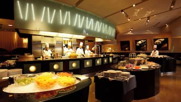 A buffet setup with various food items and a kitchen area in the background.