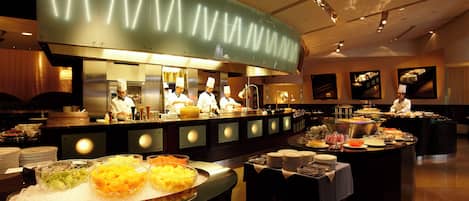 A buffet setup with various food items and a kitchen area in the background.