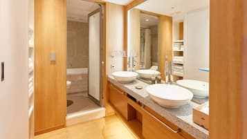 A modern bathroom with two sinks, a large mirror, and a walk-in shower.