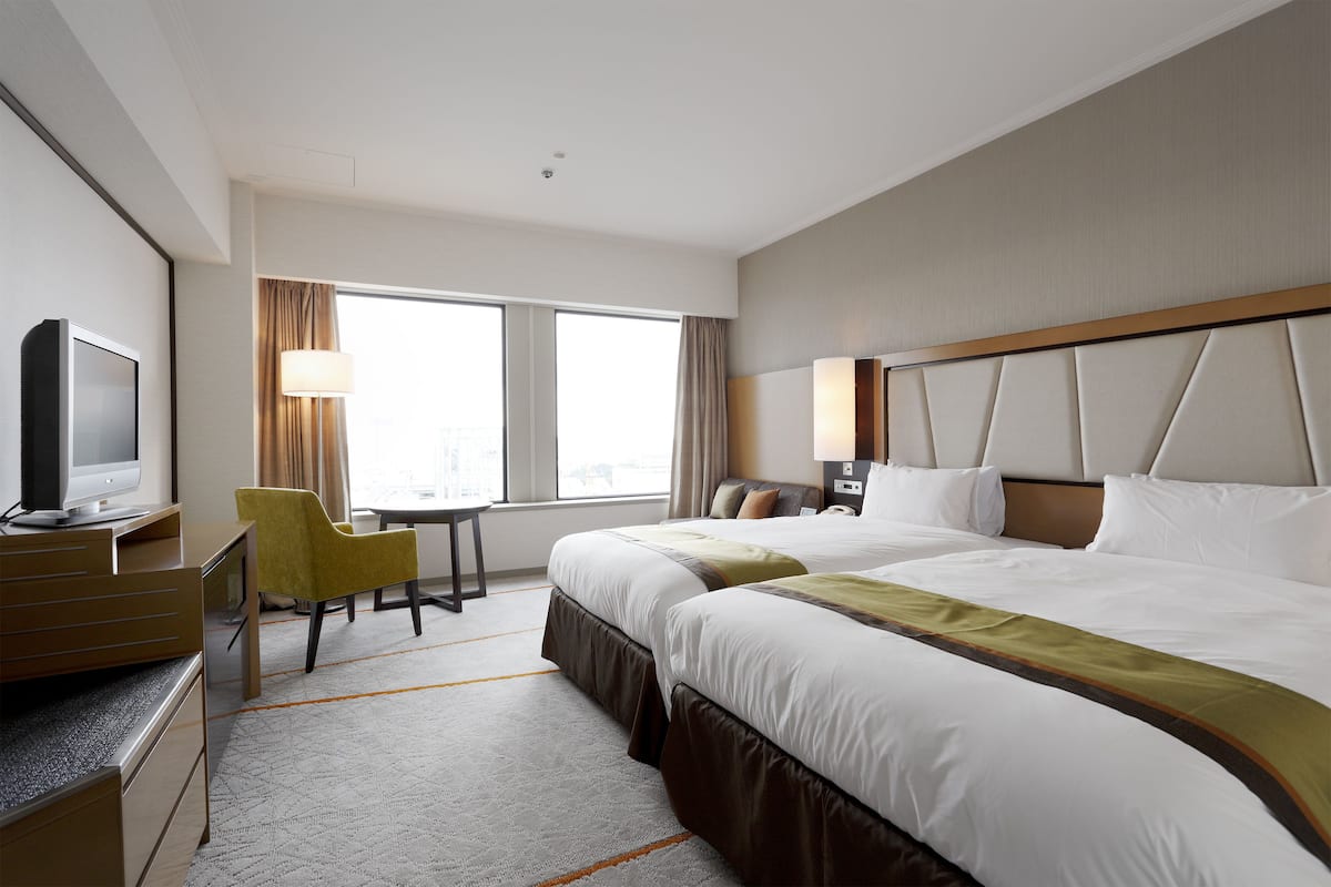 A hotel room with a bed, a desk, a chair, and a television.