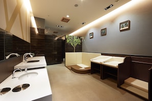 A modern bathroom with three sinks, a large mirror, and a small tree decoration on the wall.