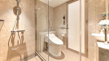 A modern bathroom with a glass-enclosed shower, a toilet, and a sink.