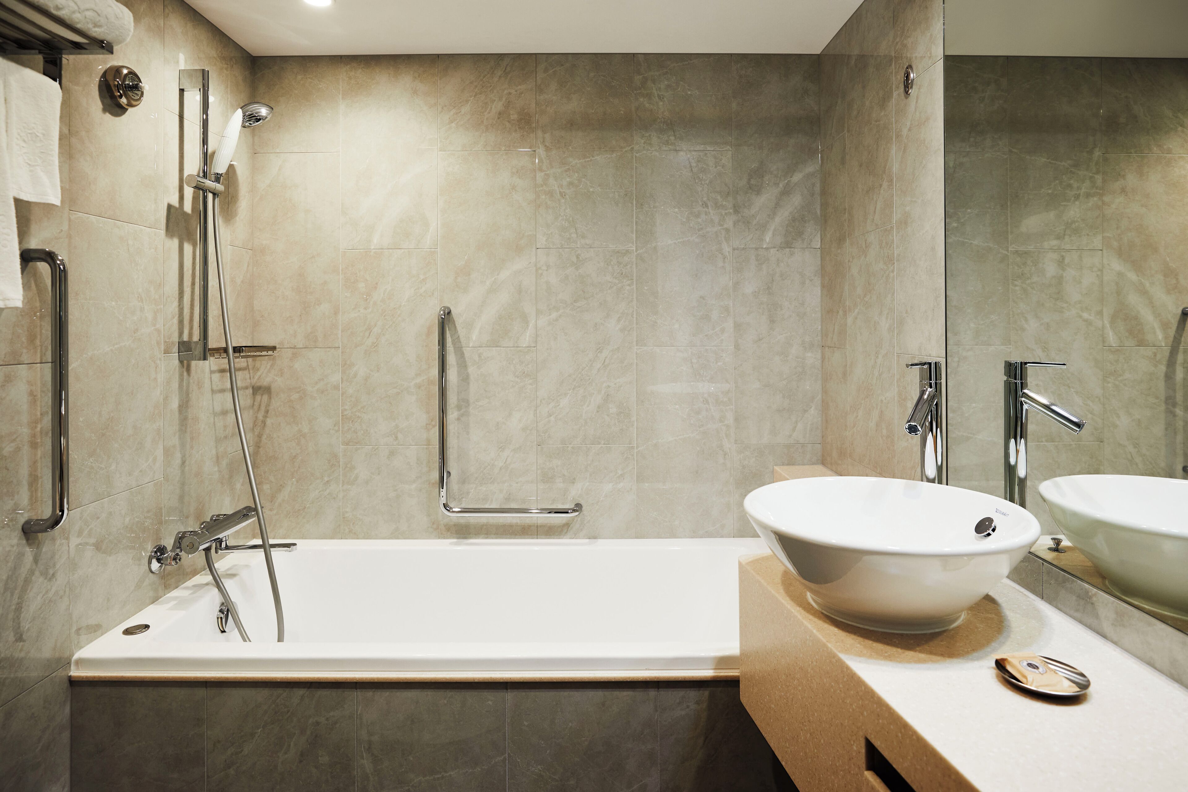 A modern bathroom with a bathtub, two sinks, and a shower.