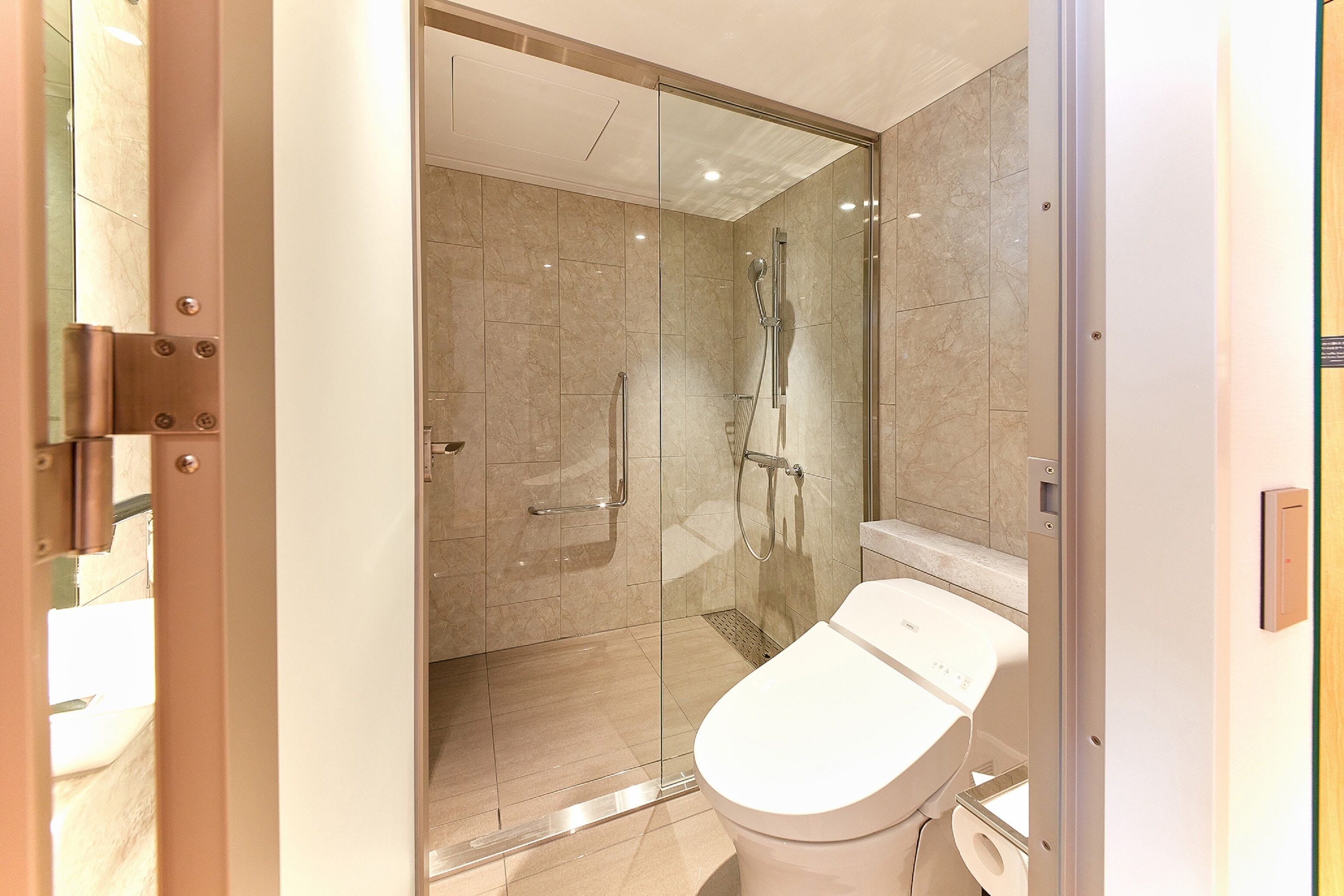 A modern bathroom with a glass-enclosed shower, a toilet, and a sink.