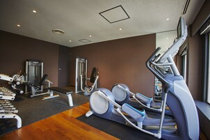 Uma academia com equipamentos de exercícios, um banco e um espelho na parede.