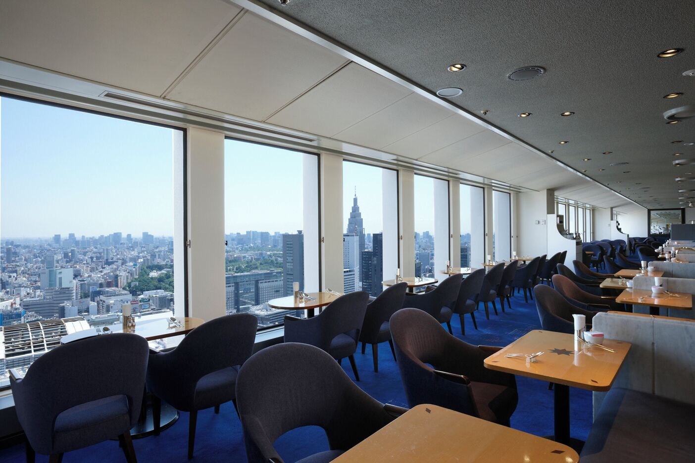 Un restaurante de altura con vistas panorámicas de la ciudad, asientos modernos y un interior amplio y luminoso.