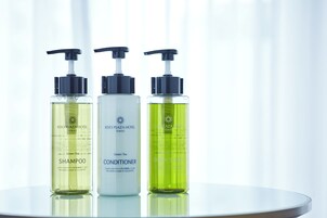 Tres botellas de productos del Hotel Keio Plaza Tokyo: champú de té verde, acondicionador y atomizador corporal.
