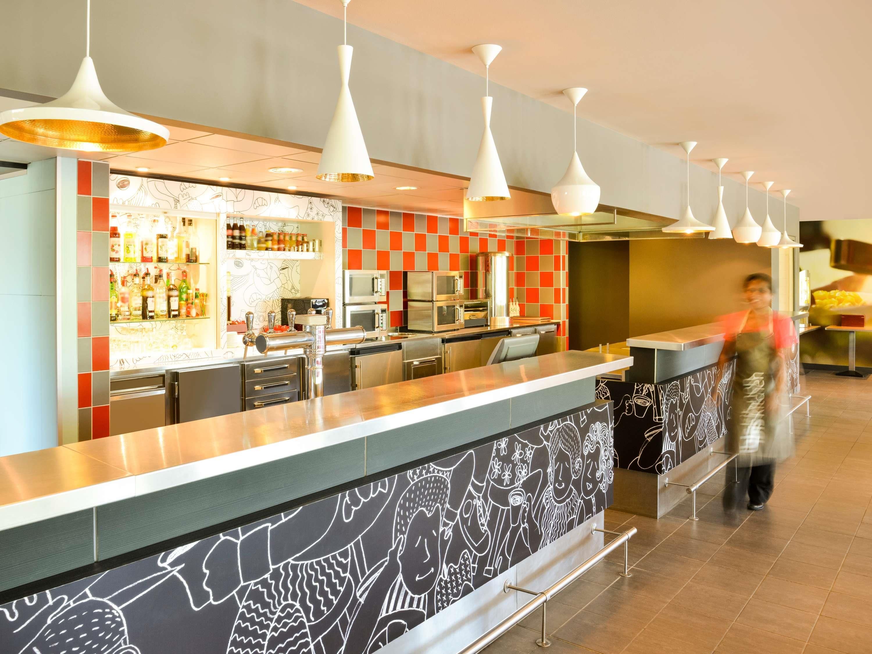 Una cocina moderna con electrodomésticos de acero inoxidable, una zona de bar con botellas y una pared con diseño.