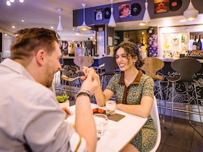 Uma área de refeições com mesa, cadeiras e um bar ao fundo.