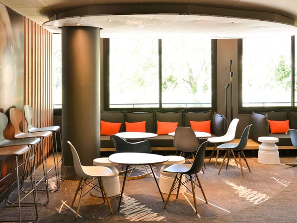 A modern lounge area with seating, tables, and large windows. - ibis Avignon Centre Gare (Avignon)
