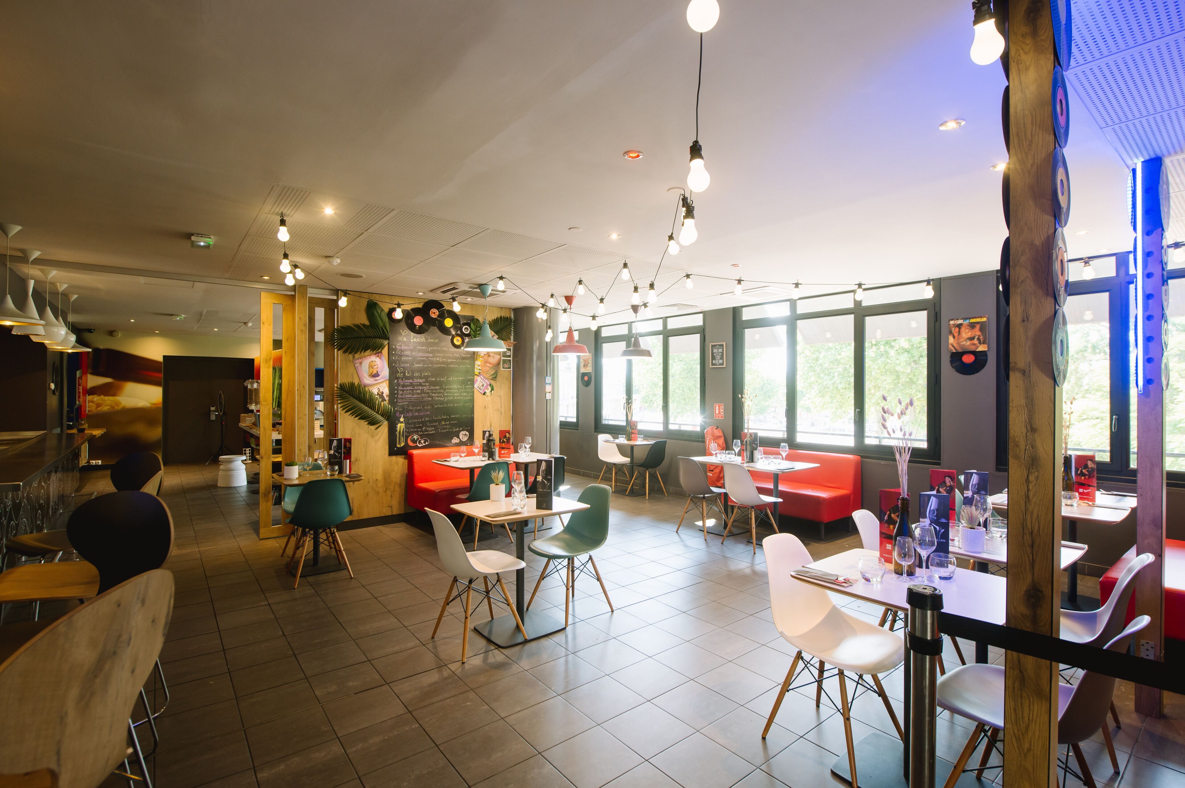 A modern restaurant interior with multiple seating areas, including booths and tables.