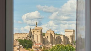 A historic building with multiple towers and a statue on top, viewed through a window. - ibis Avignon Centre Gare (Avignon)