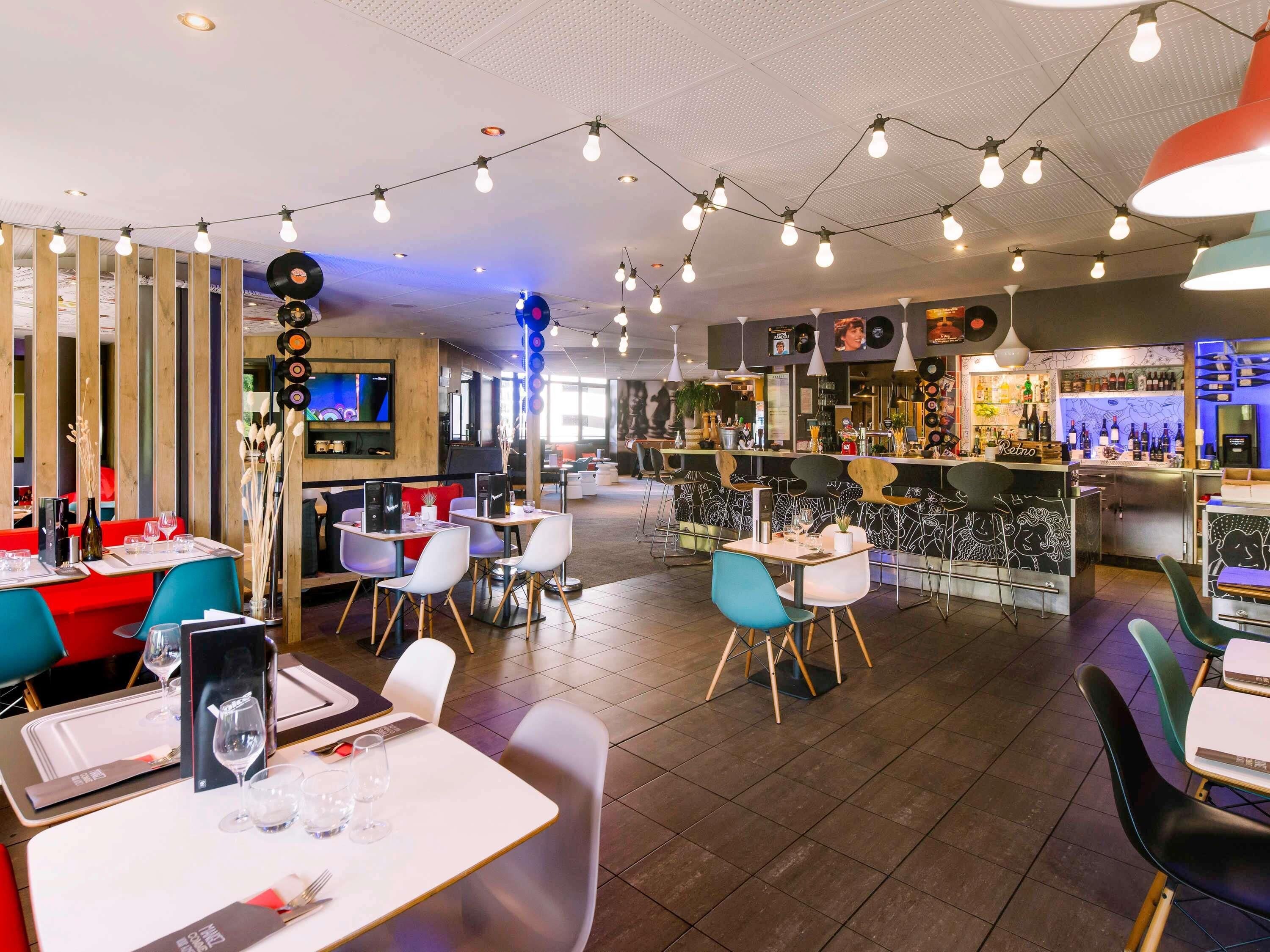 Un restaurant avec des tables et des chaises, un coin bar et un écran de télévision.