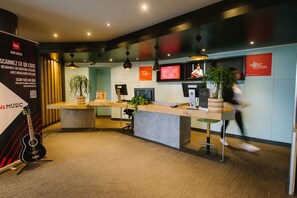 A modern reception area with a wooden reception desk, a potted plant, and a guitar on display. - ibis Avignon Centre Gare (Avignon)