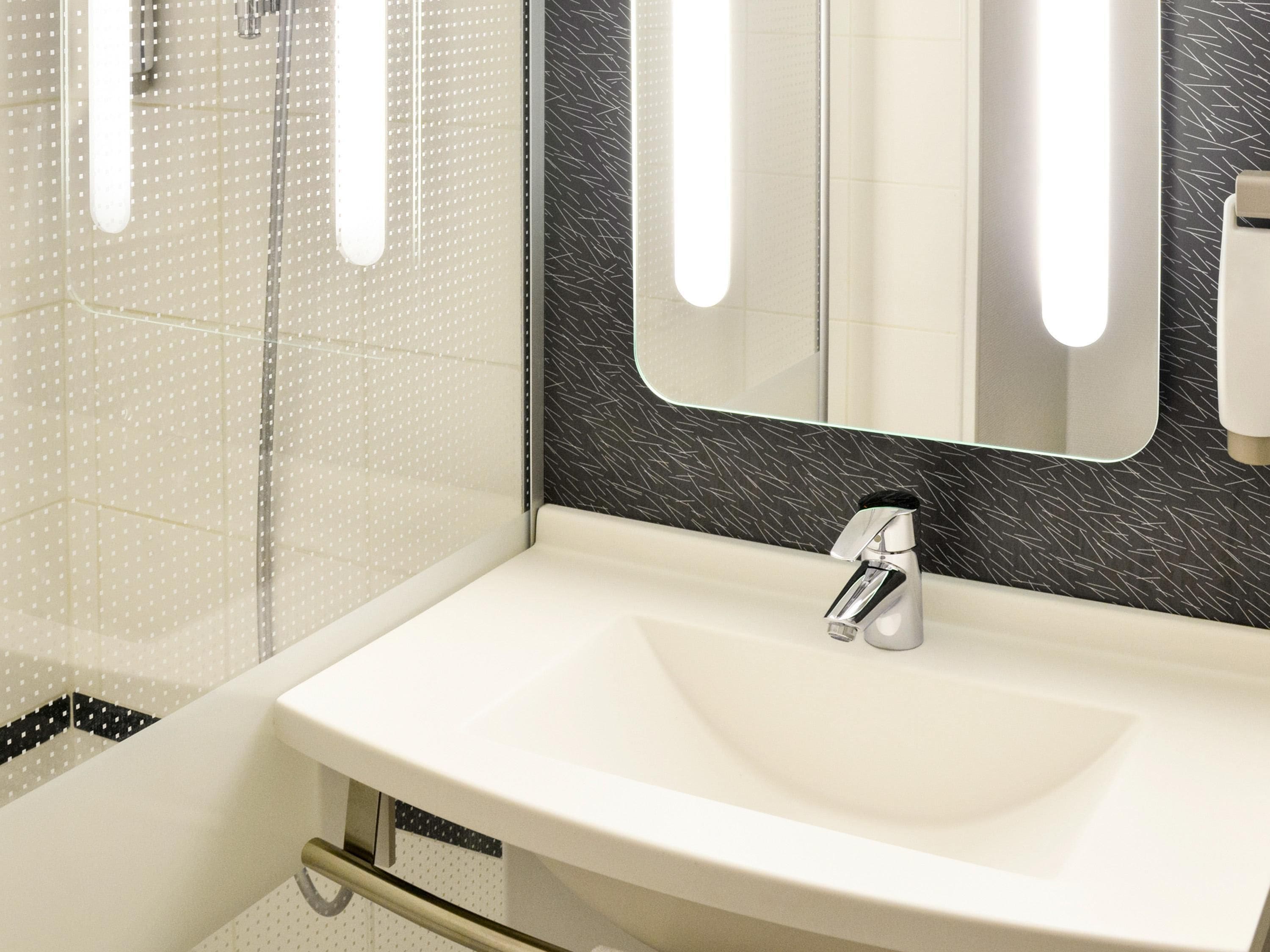A bathroom with a white sink, a mirror, and a shower area.