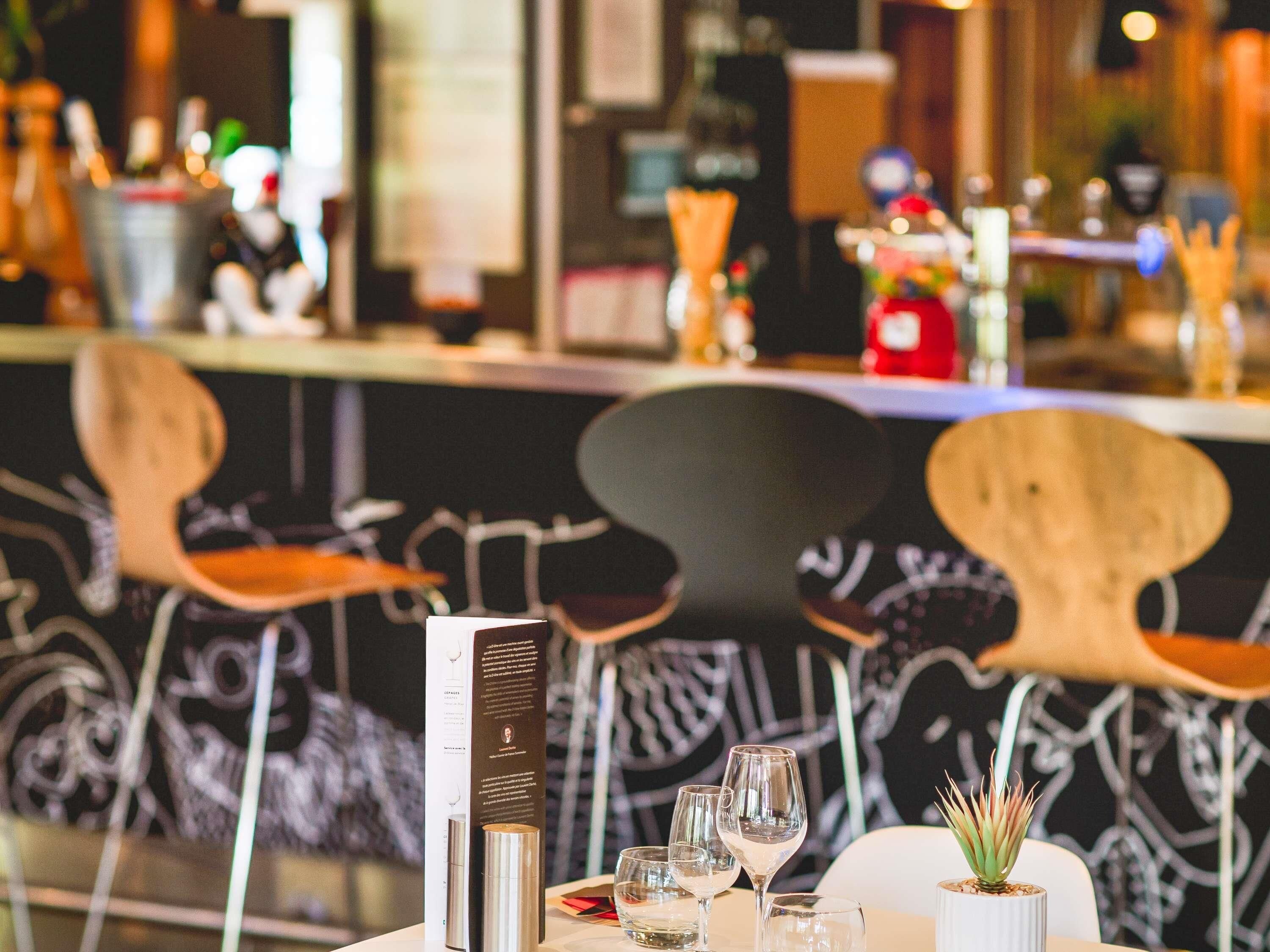 A restaurant interior with a bar area, wooden chairs, and a menu stand.