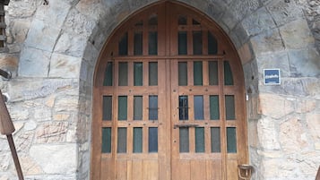 A large wooden door with glass panels, set in a stone archway.
