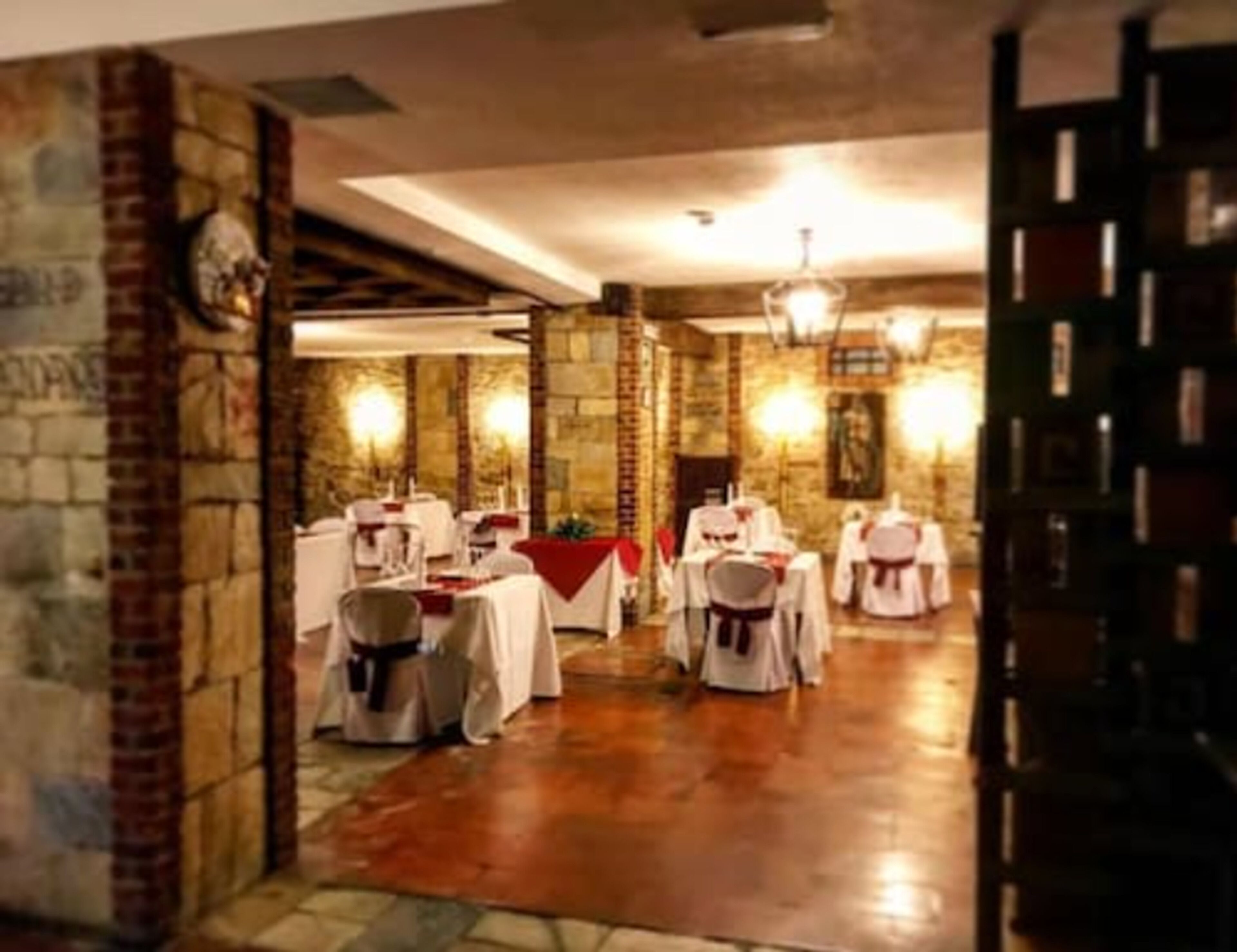 A banquet hall with tables set for a formal event, stone walls, and a chandelier.