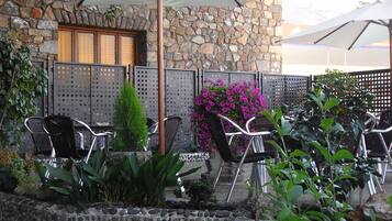Eine Terrasse im Freien mit Steinmauern, Metallstühlen und Topfpflanzen.