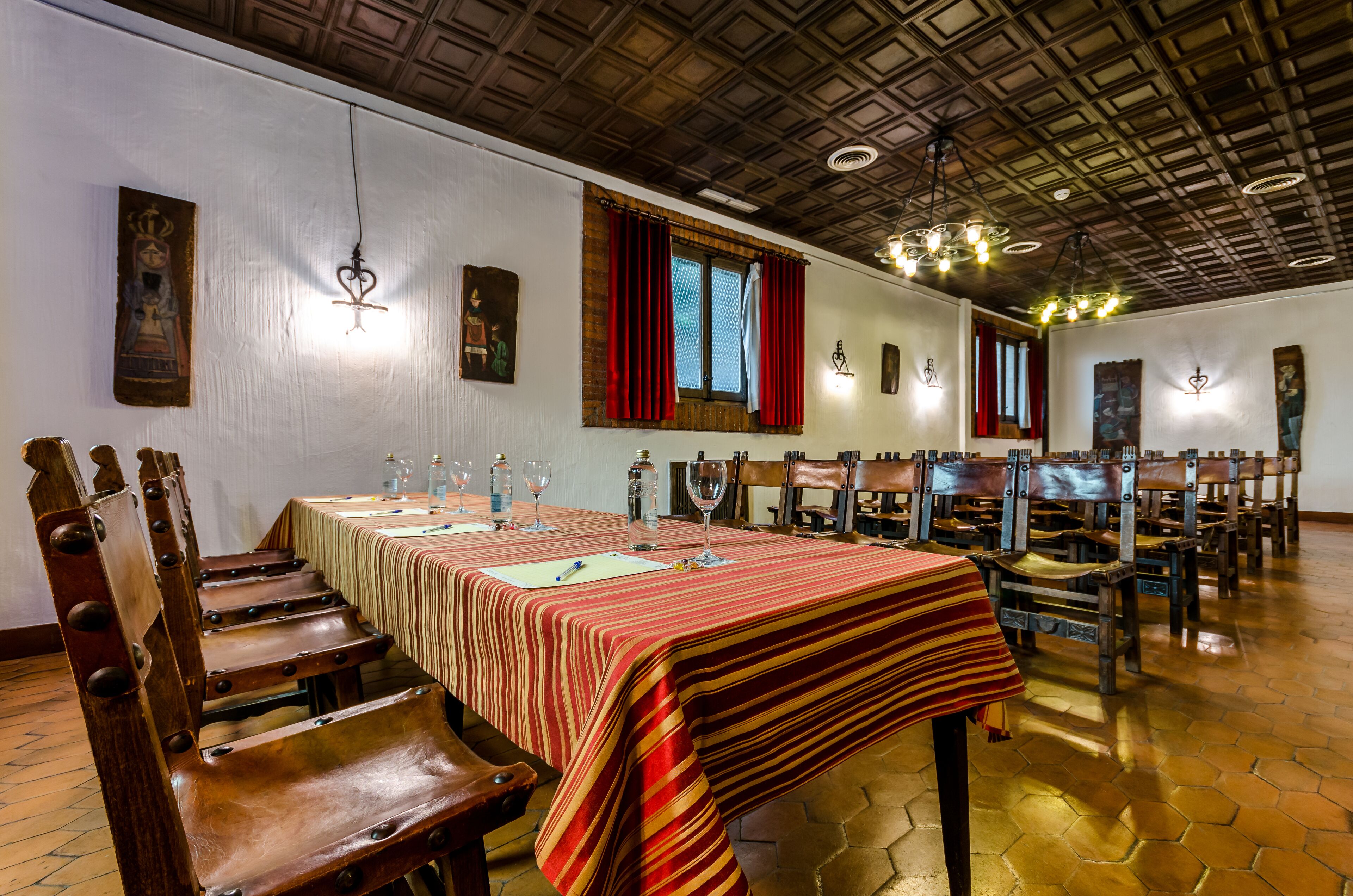 Un comedor con una larga mesa, sillas de madera y un mantel estampado.