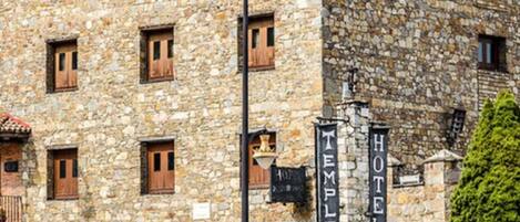 A stone building with multiple windows and a sign indicating it is a hotel.