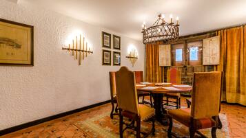 Un comedor con una mesa de madera, sillas, una araña y una alfombra estampada.