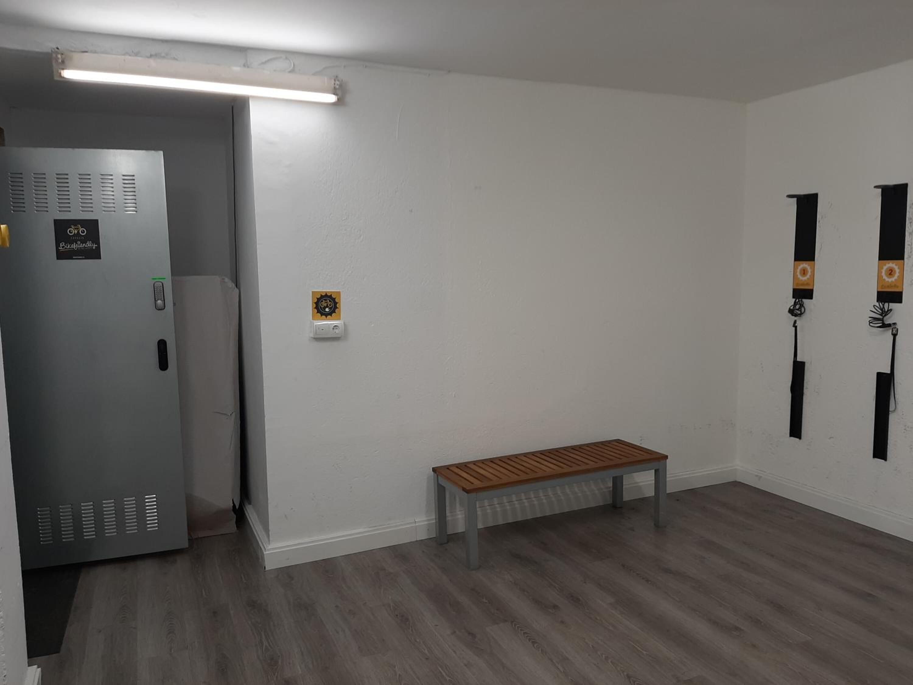 A room with a bench, a door with a security panel, and a wall-mounted light fixture.