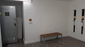 Una habitación con un banco, una puerta con panel de seguridad y un aplique.
